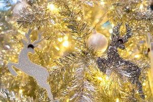 cierra la decoración del árbol de navidad con bolas blancas, renos plateados y osos rojos y luz dorada. fondo de navidad. fondo de navidad y feliz año nuevo. fondo para el tema de la Navidad. foto