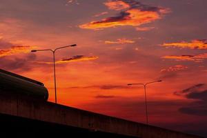 Bottom view of elevated concrete highway with sunset sky. Overpass concrete road. Road flyover structure. Modern motorway. Transportation infrastructure. Concrete bridge engineering construction. photo