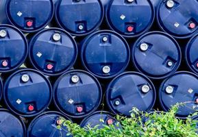 Closeup stack of chemical barrels. Blue oil drum. Plastic oil tank. Toxic waste warehouse. Hazard chemical barrel with warning label. Industrial waste in plastic drum. Hazard waste storage in factory. photo