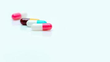Selective focus on antibiotic capsule pill. Pharmaceutical industry. Prescription drugs. Pharmacy web banner. Pink, blue, yellow, red capsules pill on white background. Antibiotic drug resistance. photo