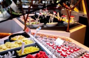 Fresh red watermelon slices in a bowl on counter bar near sweet dessert buffet. Tropical fruit buffet at event in restaurant. Catering food. Banquet service. Fruit buffet catering. Healthy snack. photo