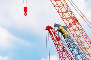 Crawler crane against blue sky and white clouds. Real estate industry. Red crawler crane use reel lift up equipment in construction site. Crane for rent. Crane dealership for construction business. photo