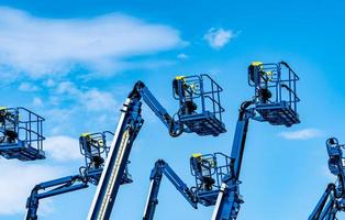 Articulated boom lift. Aerial platform lift. Telescopic boom lift against blue sky. Mobile construction crane for rent and sale. Maintenance and repair hydraulic boom lift service. Crane dealership. photo