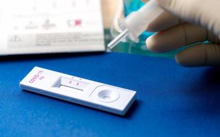 Hand holding sample tube and drops in the test device of covid 19 antigen self test. Antigen test kit for detection of coronavirus infection. Rapid antigen test. Coronavirus diagnosis. Medical device. photo