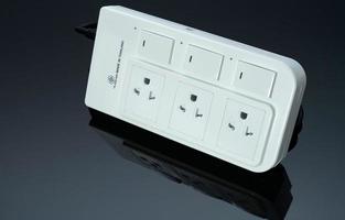 Power strip with three electrical standard socket on black background. White universal plug with overload protection. Fire resistant material for cover. Circuit breaker. Individual switch. Power plug. photo