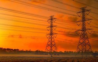 High voltage electric pylon and electrical wire with sunset sky. Electricity poles. Power and energy concept. High voltage grid tower with wire cable. Beautiful red-orange sunset sky. Infrastructure.