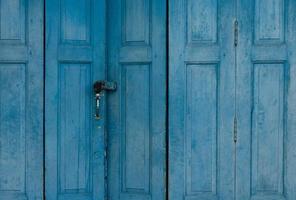 Closed blue wooden door. Vintage front door abstract background. Abandoned old house. Old wooden door texture. Lock the door of old home. Exterior vintage architecture.