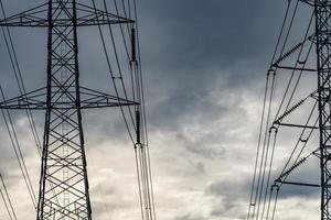 High voltage electric pylon and electrical wire against stormy sky and clouds. Bottom view of electric pylon. High voltage grid tower with wire cable. Transmission lines on high voltage grid tower. photo