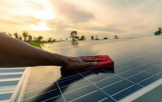 Man cleaning solar panel on roof. Solar panel or photovoltaic module maintenance. Sustainable resource and renewable energy for go green concept.  Solar power for green energy. Technology for future. photo