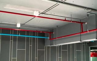 Automatic fire sprinkler safety system and red water supply pipe. Fire Suppression. Fire protection and detector. Fire sprinkler system with red pipe hanging from ceiling inside building. Wiring tube. photo