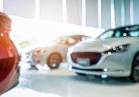 Blurred front view of white car. Luxury car parked in modern showroom. Car dealership office. Electric car business concept. Automobile leasing. Automotive industry crisis impact from coronavirus. photo