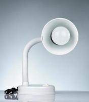 White modern table lamp isolated on white table on gradient background. Desk lamp for reading a book in dormitory room. Home and office furniture with minimalist design. Desk spotlight. photo