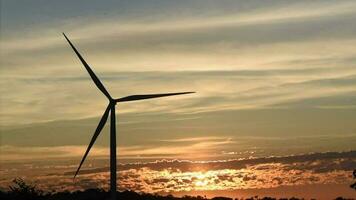 siluetas de generadores de energía de turbinas eólicas al atardecer. cielo al atardecer con rayos de sol video