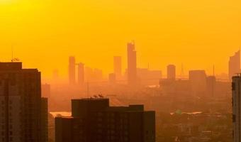Air pollution. Smog and fine dust of pm2.5 covered city in the morning with orange sunrise sky. Cityscape with polluted air. Dirty environment. Urban toxic dust. Unhealthy air. Urban unhealthy living. photo
