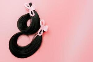 Hair donation for breast cancer person. Donate hair to wigs for breast cancer and leukemia patients. Donate to cancer charity. Long human hair with hair clip claw for donation on pink background.