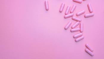 Pink antibiotic capsule pills spread on pink background. Antibiotic drug resistance. Pharmaceutical industry. Healthcare and medicine concept. Health budget concept. Capsule manufacturing industry. photo