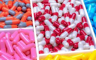 Red-white, orange-gray, pink, blue, and yellow capsules in plastic tray. Antibiotic capsule pills. Pharmaceutical industry. Drug of choice for treatment infections. Antimicrobial drugs resistance. photo