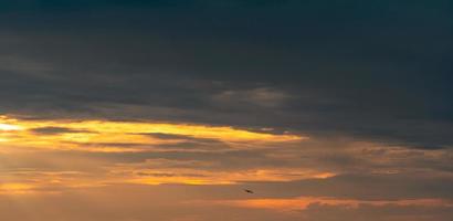 silueta pequeño avión volando en el hermoso cielo del atardecer. vasto cielo dorado del atardecer. libertad y fondo tranquilo. belleza en la naturaleza. escenario poderoso y espiritual. cielo dorado dramático y majestuoso. foto