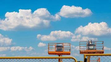 Articulated boom lift. Aerial platform lift. Telescopic boom lift against blue sky. Mobile construction crane for rent and sale. Maintenance and repair hydraulic boom lift service. Crane dealership. photo