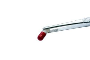 Forceps pick red-white capsule pill isolated on white backgroud. Drugs choose. Drug selection. QA and QC in pharmaceutical industry. Drugs of choice. Capsule pill in laboratory for quality test. photo