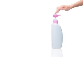 Woman hand pressed on pump cosmetic bottle isolated on white. Shampoo or hair conditioner plastic bottle and dispenser pump. Body soap or shower gel packaging. Liquid soap bottle. Body lotion bottle. photo