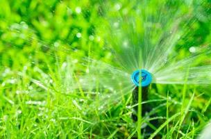 Automatic lawn sprinkler watering green grass. Sprinkler with automatic system. Garden irrigation system watering lawn. Water saving or water conservation from sprinkler system with adjustable head. photo