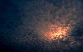 luz roja del sol en el oscuro cielo nublado del atardecer. cielo dramático con un hermoso patrón de nubes esponjosas. Fondo de poder mental o poder psíquico. poder de la naturaleza. nubes exóticas. concepto de cambio climático. foto