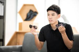 online sale and social media marketing concept, young Asian man working with camera to live streaming to sale a product and showing packet to review, broadcast cyberspace and blog shop