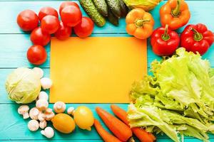 Different vegetables on kitchen table with recipe list and copy space. Top view photo