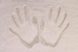 The imprint of two human palms on the sand from above photo