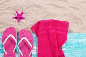 Summer towels, flip flops and pink starfish on the sand top view photo