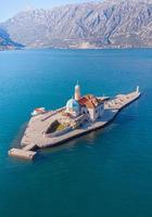 Perast, Montenegro 2022 - Aerial view taken with drone of the artificial island of the Church of Our Lady of the Rocks during a summer sunny day on the shores of Perast in Kotor Bay, Montenegro photo