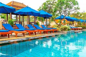 Beautiful umbrella and chair around swimming pool in hotel and resort photo