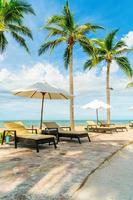 Beautiful tropical beach and sea with umbrella and chair around swimming pool in hotel resort photo