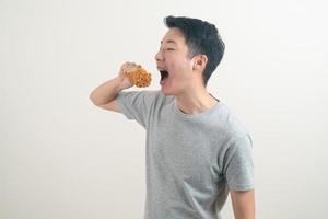 joven asiático con pollo frito en la mano foto
