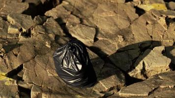black trash bag lay on a rocky beach video