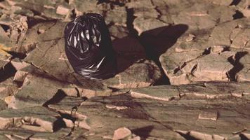 black trash bag lay on a rocky beach video