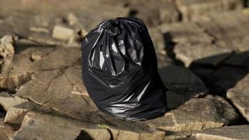 bolsa de basura negra yacía en una playa rocosa video