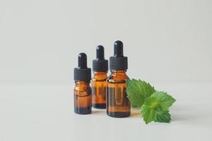 Peppermint extract or Peppermint essential oil in a brown bottle with a sprig of fresh green mint. photo