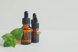 Peppermint extract or Peppermint essential oil in a brown bottle with a sprig of fresh green mint. photo