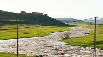 Ruines du château de kimav sur la colline de l'autre côté de la route au coucher du soleil avec cheval dans l'est de l'anatolie, turquie