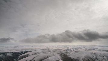 Movimientos de nubes de 8k en un parche de colinas invernales cubiertas de nieve