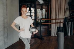 Smiling fit female posing with pilates ball in fitness studio photo