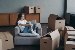 la mujer feliz es compradora de apartamentos. la empresa de mudanzas sueña entre cajas en la sala de estar de un nuevo hogar. foto