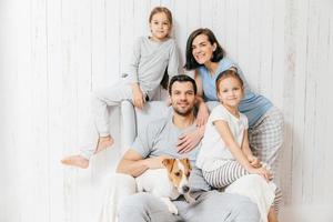 Friendly family of four memebers cheerful European brunette female, her husband, two daughters and favourite pet, have good relationships, support each other. Affectionate parents with children photo