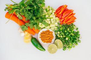 Flat lay of cut fresh vegetables. Healthy carrot, green onion, parsley, lime, garlic, jalapeno against white background. Vegetable mix for vegans. Food concept. photo