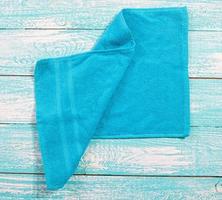 Blue towel top view on wooden blue board close up copy space. Blue soft napkin closeup photo