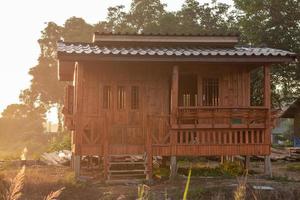 pequeña casa de madera con sol en el campo tailandés. foto
