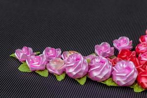 Artificial pink roses on a red background, black, corrugated. photo