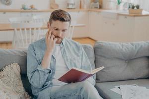 Young pensive handsome man finding new ideas and writing them down photo